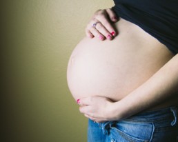 pregnant woman standing behind wall